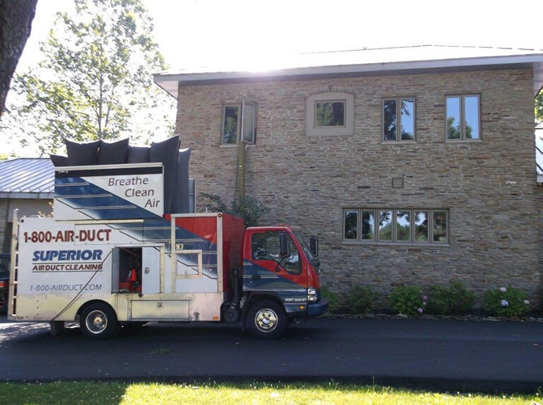 Superior Air Duct Cleaning truck in front of residence with sun in background